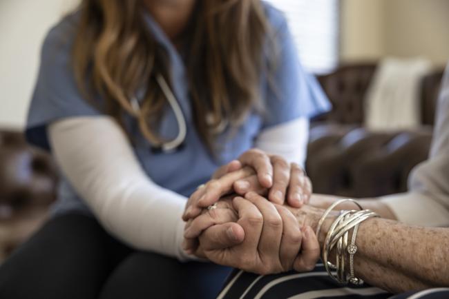 Home healthcare nurse holding hands of elderly patient